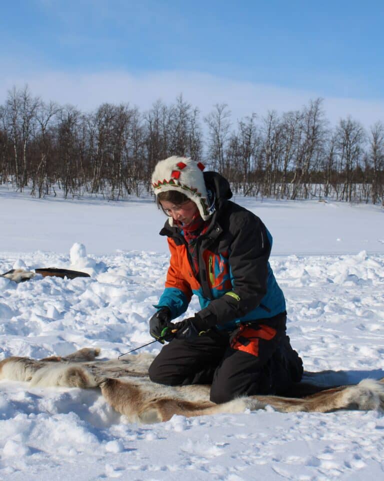 A woman ice fishing in the wilderness in Enontekiö Lapland.
